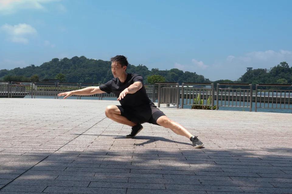 Nate Gan demonstrating a controlled lateral squat outdoors